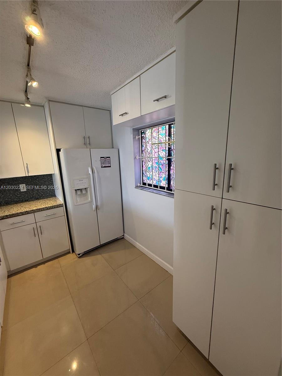 A kitchen features white cabinetry, a white refrigerator, granite countertops, and a stained-glass window — 8625 NW 8th St # 420, Miami FL 33126, MIAMI, FL
