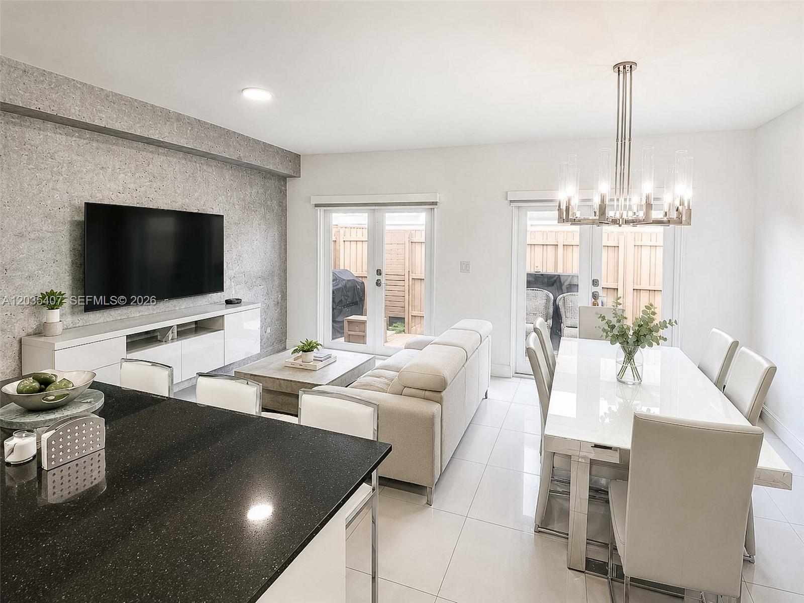 An open-concept living and dining area features a textured accent wall and white tile flooring — 14467 SW 260th St, Homestead FL 33032, HOMESTEAD, FL