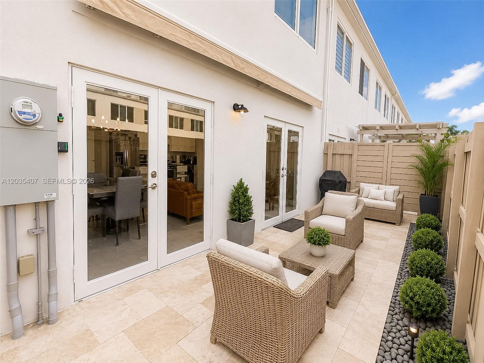 A patio with wicker furniture, potted plants, and stone pavers sits outside a white building — 14467 SW 260th St, Homestead FL 33032, HOMESTEAD, FL