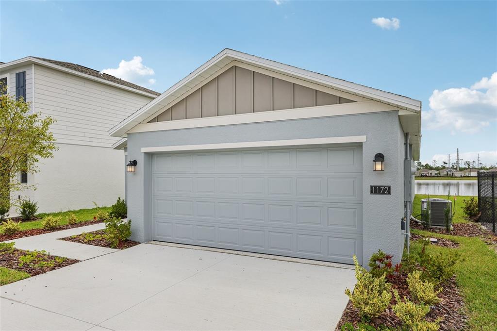 A light blue single-car garage exterior with a concrete driveway and a tan gable roof — 1172 BELLE ISLE LANE, DAYTONA BEACH, FL