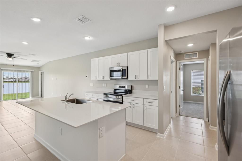 A kitchen with white cabinets, quartz countertops, a center island, and stainless steel appliances — 1172 BELLE ISLE LANE, DAYTONA BEACH, FL