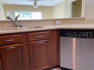 A kitchen features wood cabinets, a stainless steel dishwasher, and a sink with a faucet — 20418 NEEDLETREE DRIVE, TAMPA, FL