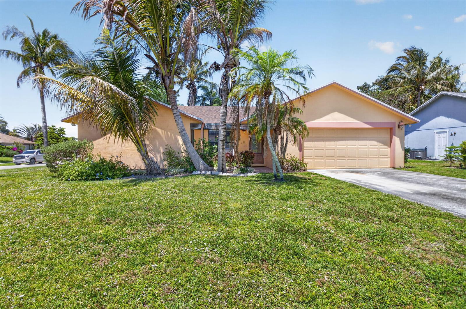 A single-story house with a tan exterior, a two-car garage, and several palm trees — 9389 Longmeadow Circle, Boynton Beach FL 33436, BOYNTON BEACH, FL