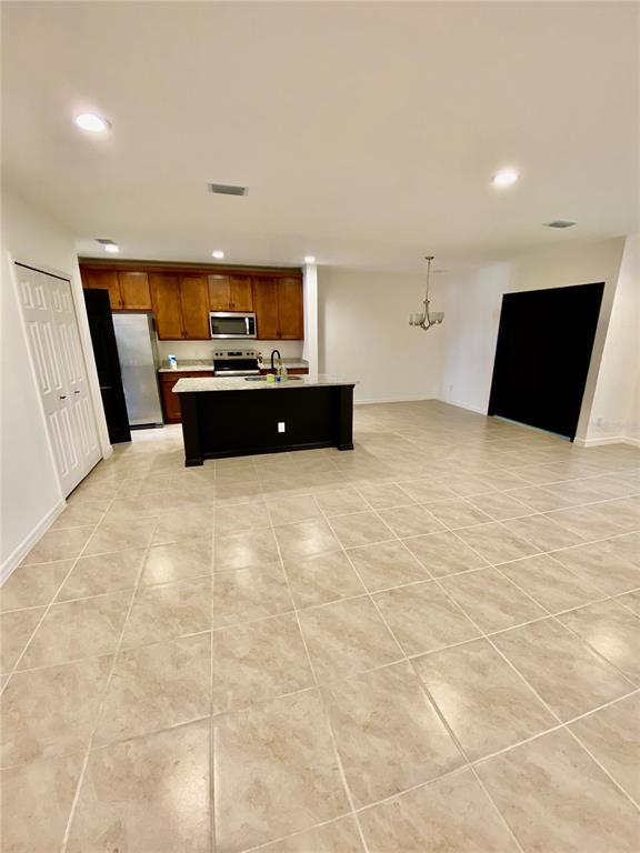 A kitchen with wood cabinets, a dark island, and tile flooring in an open room — 182 GLASS ONION DRIVE, HOWEY IN THE HILLS, FL