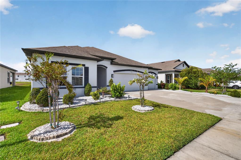A single-story house with a white stucco exterior, a two-car garage, and a landscaped lawn — 2526 SAND GABLES TRAIL, BRADENTON, FL