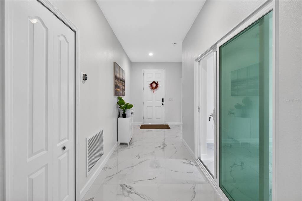 A bright entryway features white marble-look tile flooring, a white front door, and glass doors — 2526 SAND GABLES TRAIL, BRADENTON, FL