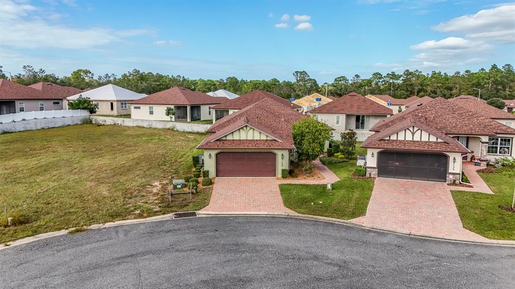 An aerial view shows two suburban houses with brick driveways next to an empty lot — 9129 S DEER PARK DRIVE, HOMOSASSA, FL
