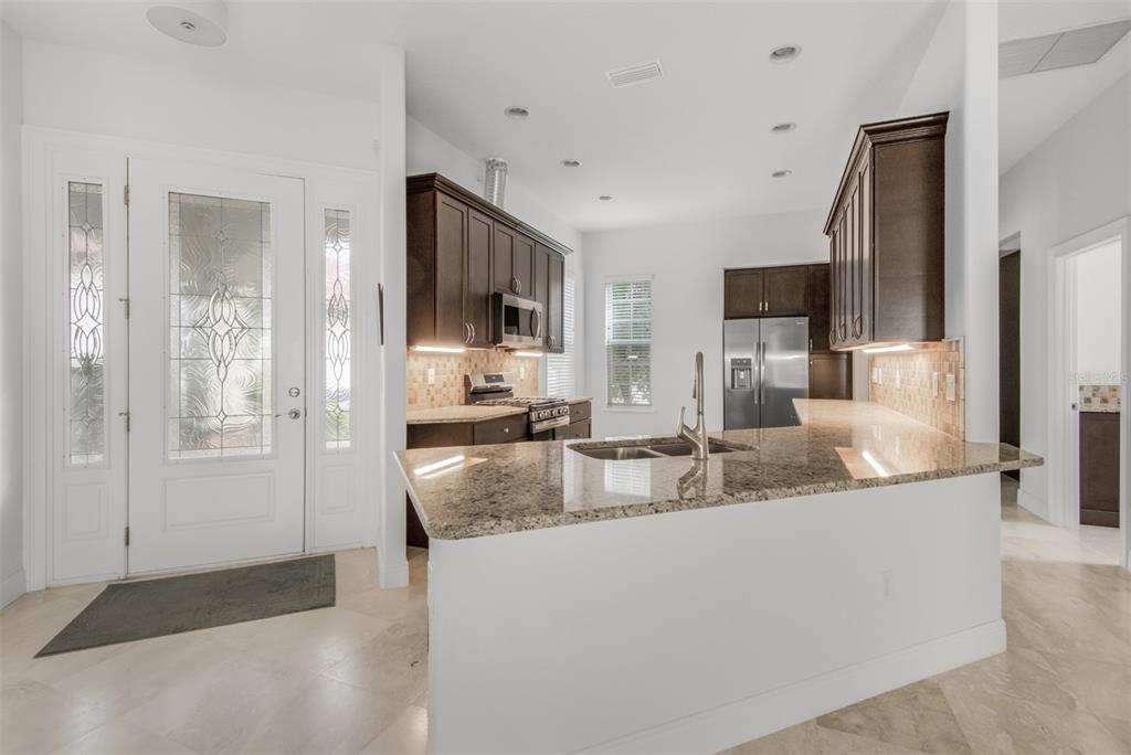 A kitchen with dark wood cabinets, granite countertops, and a breakfast bar near the entryway — 9129 S DEER PARK DRIVE, HOMOSASSA, FL