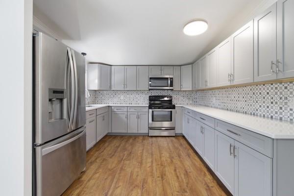 A kitchen with stainless steel appliances, light gray cabinets, white countertops, and wood-look flooring — 24225 DUFFIELD ROAD, BROOKSVILLE, FL