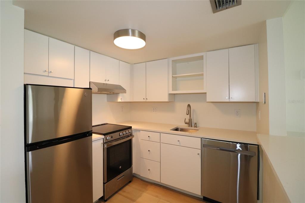 A kitchen features white cabinets, stainless steel appliances, and light-colored countertops — 618 ORANGE DRIVE UNIT 207, ALTAMONTE SPRINGS, FL