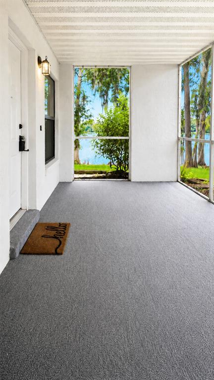 A covered porch features a white front door, a window with blinds, and gray flooring — 703 NORTHLAKE DRIVE UNIT 703, SANFORD, FL