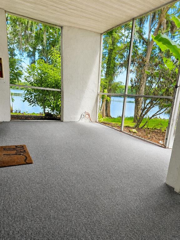 A screened-in porch with gray flooring and a view of a lake and trees — 703 NORTHLAKE DRIVE UNIT 703, SANFORD, FL