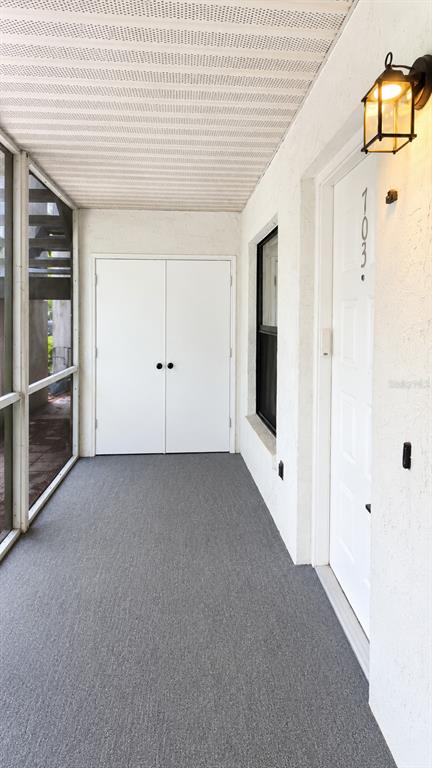 A screened-in porch with gray carpeting overlooks a lake surrounded by trees — 703 NORTHLAKE DRIVE UNIT 703, SANFORD, FL