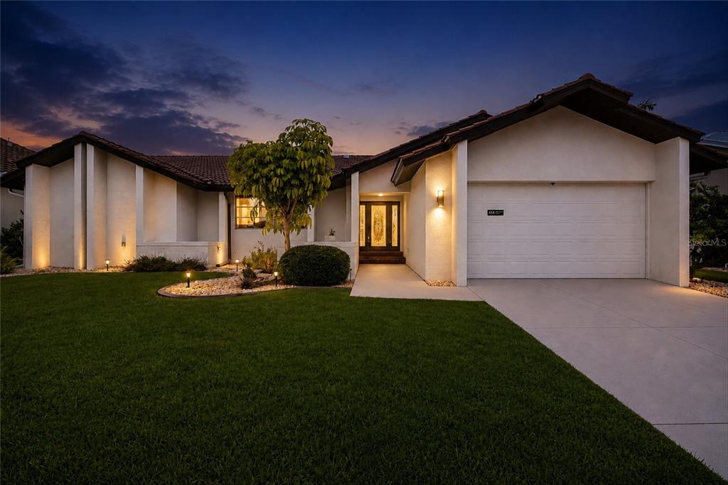A single-story house with a white stucco facade, tile roof, and attached garage at dusk — 454 MONACO DRIVE, PUNTA GORDA, FL