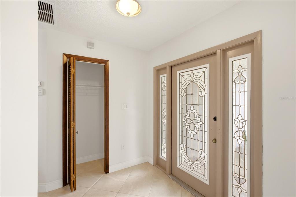 An entryway features a tiled floor, a closet with louvered doors, and a decorative glass door — 454 MONACO DRIVE, PUNTA GORDA, FL
