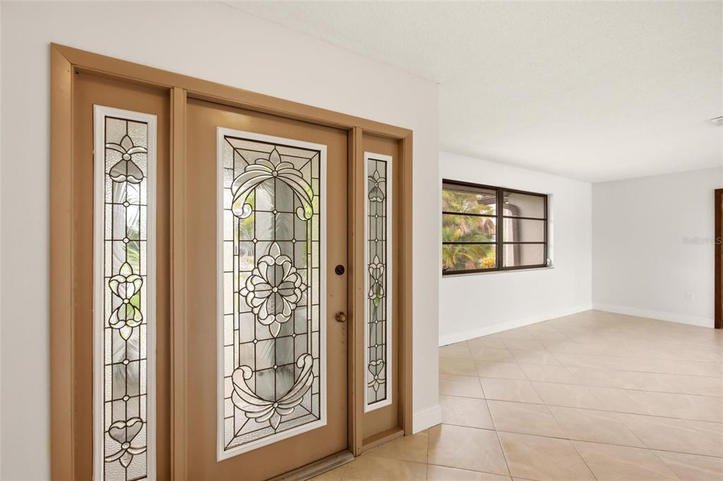 An interior view of an entryway featuring a decorative glass front door and tile flooring — 454 MONACO DRIVE, PUNTA GORDA, FL