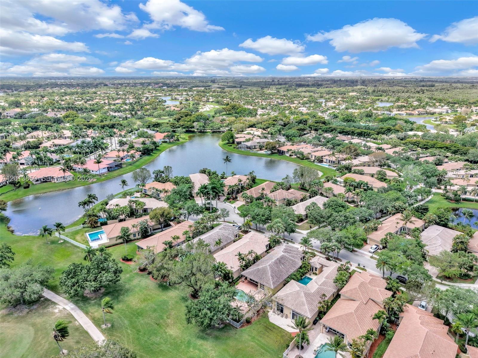 An aerial view shows a residential neighborhood with houses, swimming pools, and a central lake — 2468 Bay Isle Court, Weston FL 33327, WESTON, FL