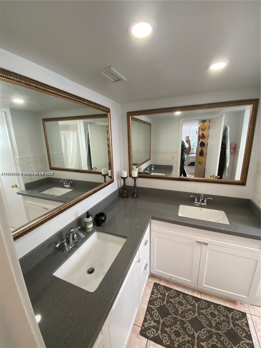 A bathroom features a double vanity with white cabinets, gray countertops, and two large mirrors — 1670 NE 191st St # 3, Miami FL 33179, MIAMI, FL