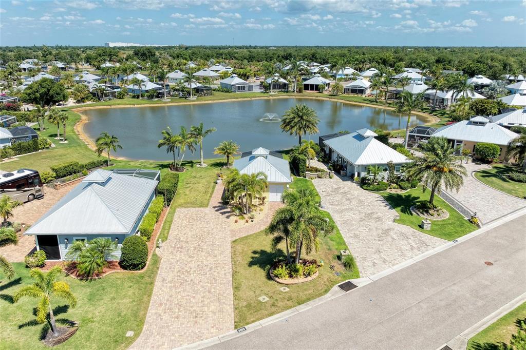 An aerial view shows three houses with metal roofs and paver driveways beside a pond — 8503 SW SAND CRANE CIRCLE LOT 74, ARCADIA, FL