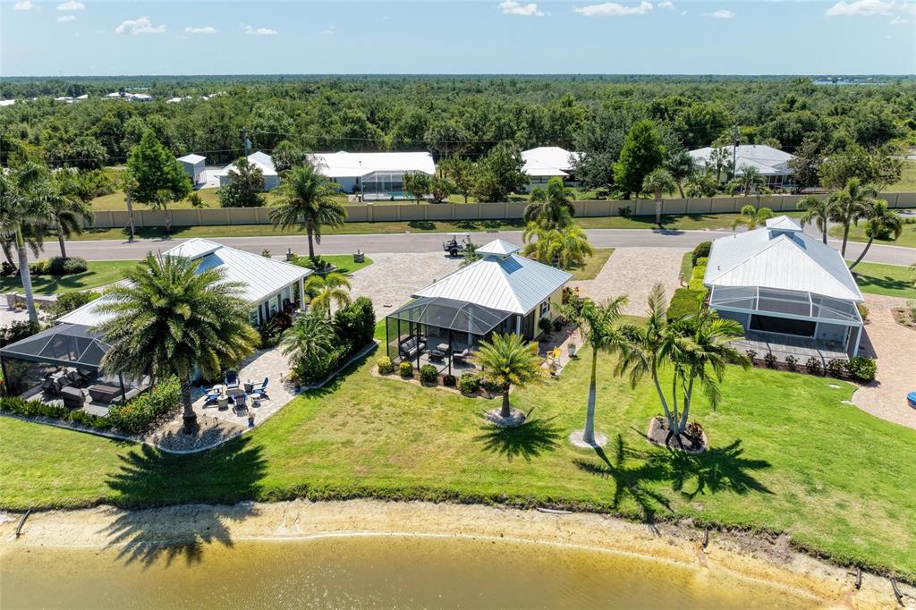 An aerial view shows three waterfront houses with screened lanais and metal roofs — 8503 SW SAND CRANE CIRCLE LOT 74, ARCADIA, FL