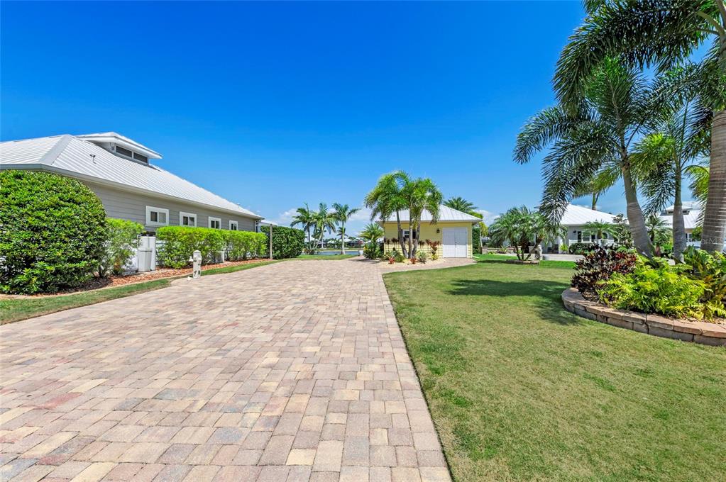 A paved driveway leads toward a yellow detached garage and a house with palm trees — 8503 SW SAND CRANE CIRCLE LOT 74, ARCADIA, FL