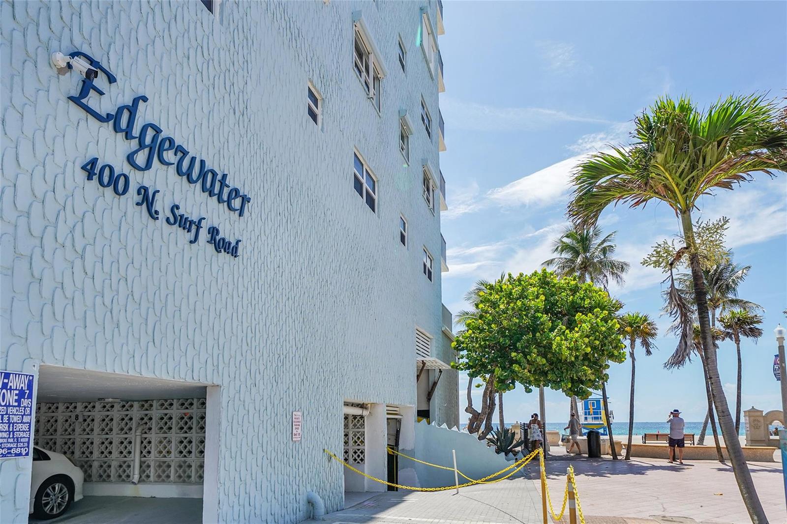 The exterior of a light blue building with palm trees and a beach in the background — 400 N Surf Road # 703, Hollywood FL 33019, HOLLYWOOD, FL