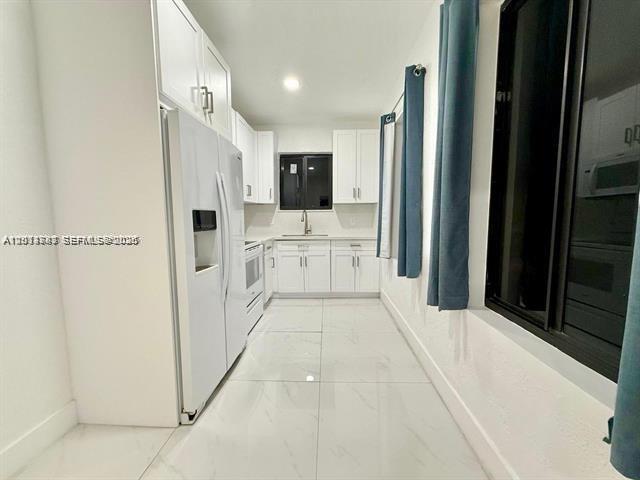 A white kitchen features tile flooring, white cabinetry, and a stainless steel refrigerator — 2369 SW 17th Ter, Miami FL 33145, MIAMI, FL
