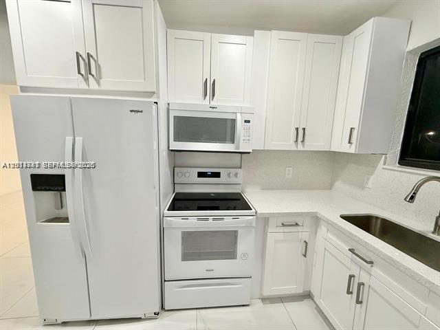 A kitchen features white cabinets, white appliances, and light-colored countertops — 2369 SW 17th Ter, Miami FL 33145, MIAMI, FL