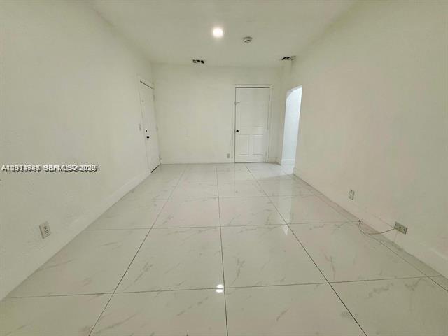 An empty room features white walls and large, light-colored marble-patterned floor tiles — 2369 SW 17th Ter, Miami FL 33145, MIAMI, FL