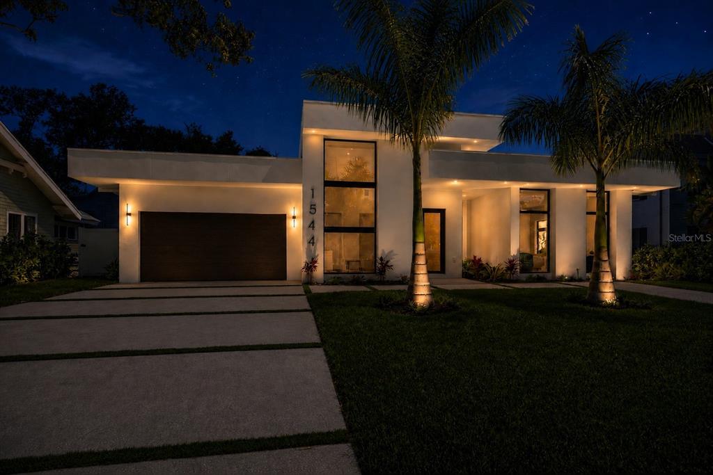 A modern white house with a flat roof and palm trees at night — 1544 3RD AVENUE W, BRADENTON, FL