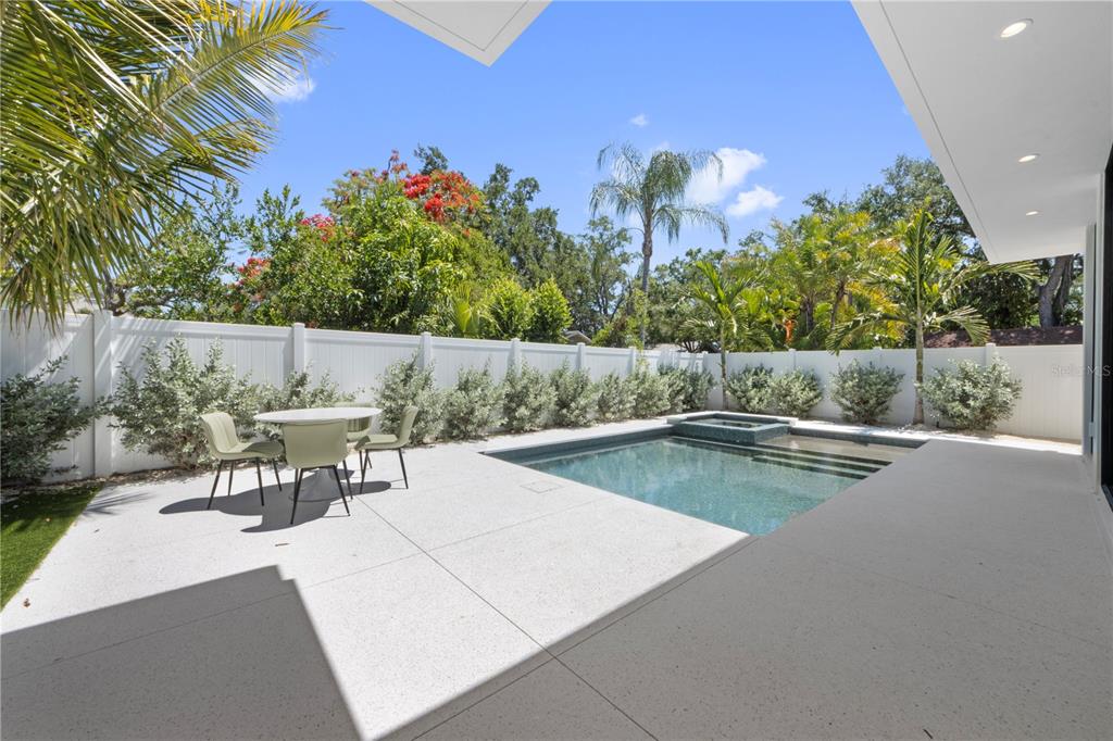 A modern backyard patio features a small swimming pool, a dining set, and white fencing — 1544 3RD AVENUE W, BRADENTON, FL