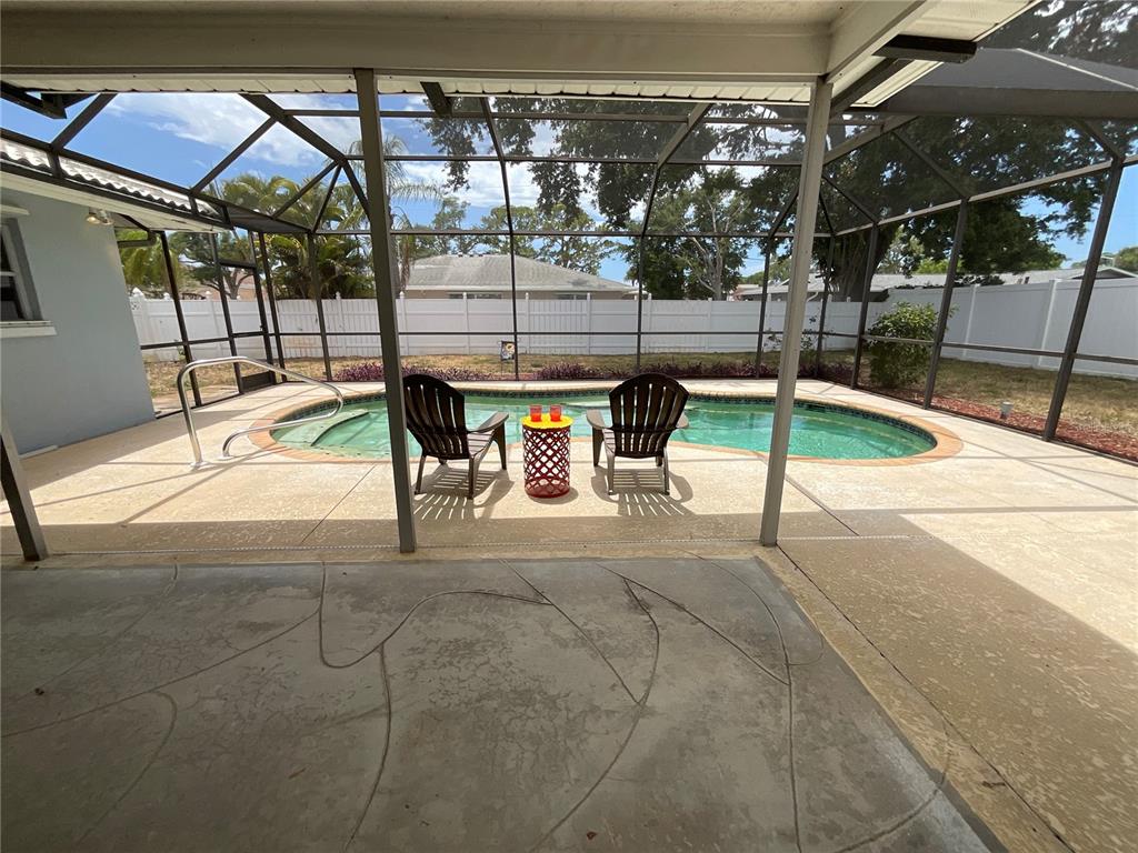 A screened-in patio features a concrete deck, a swimming pool, and two outdoor chairs — 2224 42ND STREET W, BRADENTON, FL