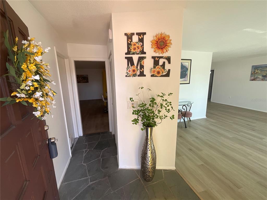 An entryway features a slate floor, a sunflower-themed wall sign, and a tall metallic vase — 2224 42ND STREET W, BRADENTON, FL
