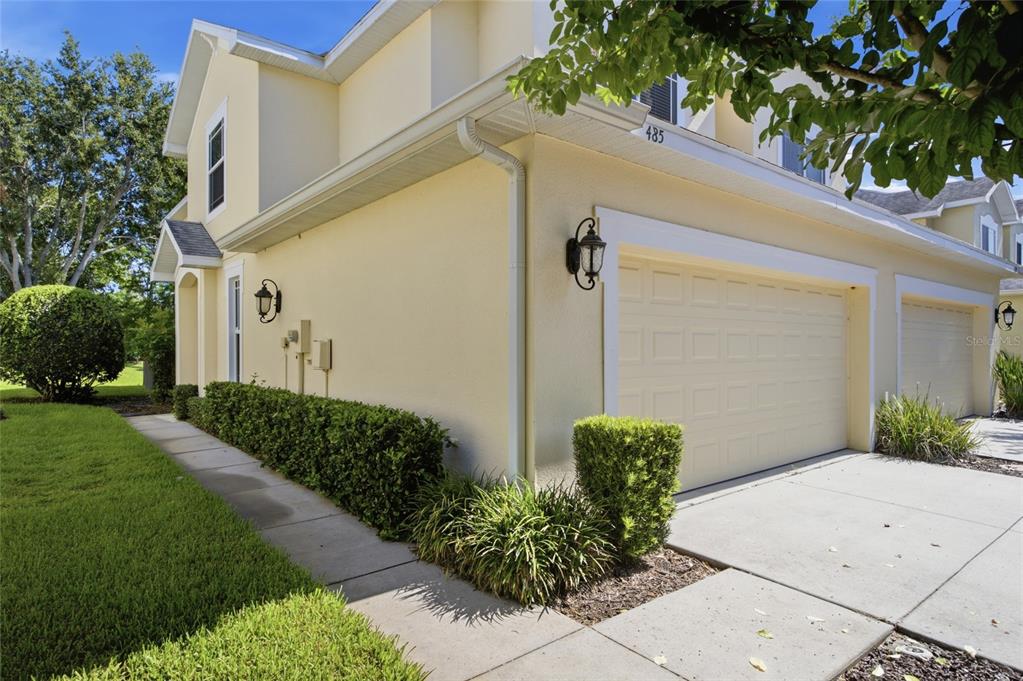 A light yellow two-story townhouse exterior features a two-car garage and a concrete walkway — 485 HARBOR RIDGE DRIVE, PALM HARBOR, FL