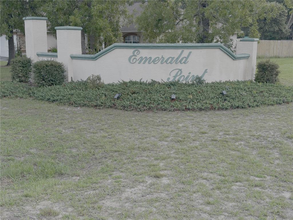 A beige stucco neighborhood entrance sign reads Emerald Point in front of a house — 10417 SW 52ND COURT, OCALA, FL