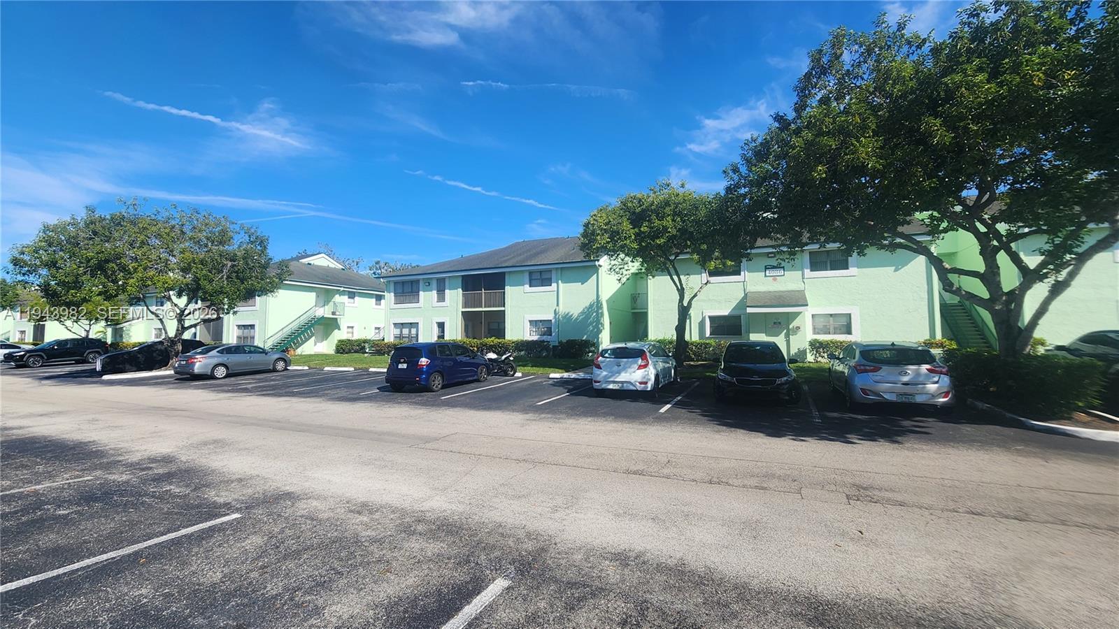 A parking lot sits in front of a two-story apartment building with light green walls — 4086 N Pine Island Rd # 510, Sunrise FL 33351, SUNRISE, FL