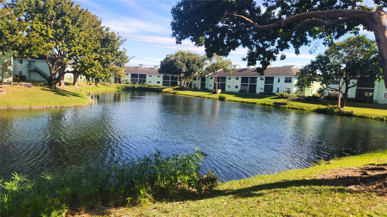 A pond sits in front of multi-story apartment buildings surrounded by green trees and grass — 4086 N Pine Island Rd # 510, Sunrise FL 33351, SUNRISE, FL