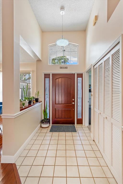 An entryway features a wooden front door, tiled flooring, a high ceiling, and louvered closet doors — 2821 LONE FEATHER DRIVE, ORLANDO, FL