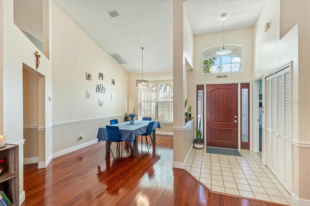 A dining area with hardwood floors and a foyer with tile flooring and a door — 2821 LONE FEATHER DRIVE, ORLANDO, FL