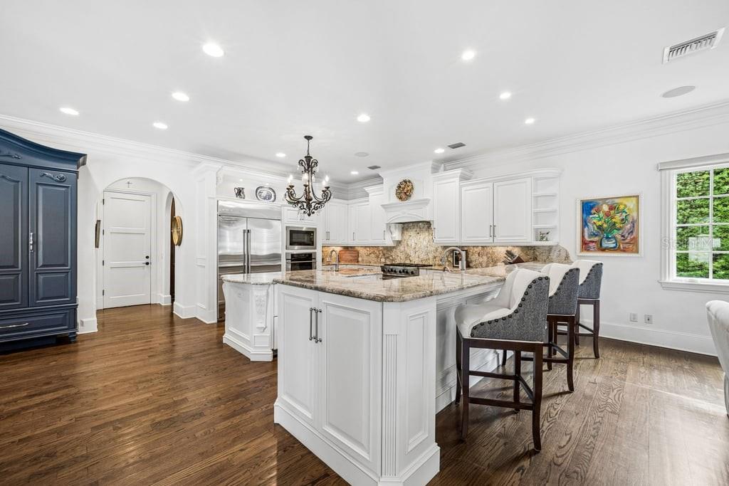 A white kitchen features a large island, granite countertops, dark wood floors, and a blue cabinet — 1571 WOODLAND AVENUE, WINTER PARK, FL