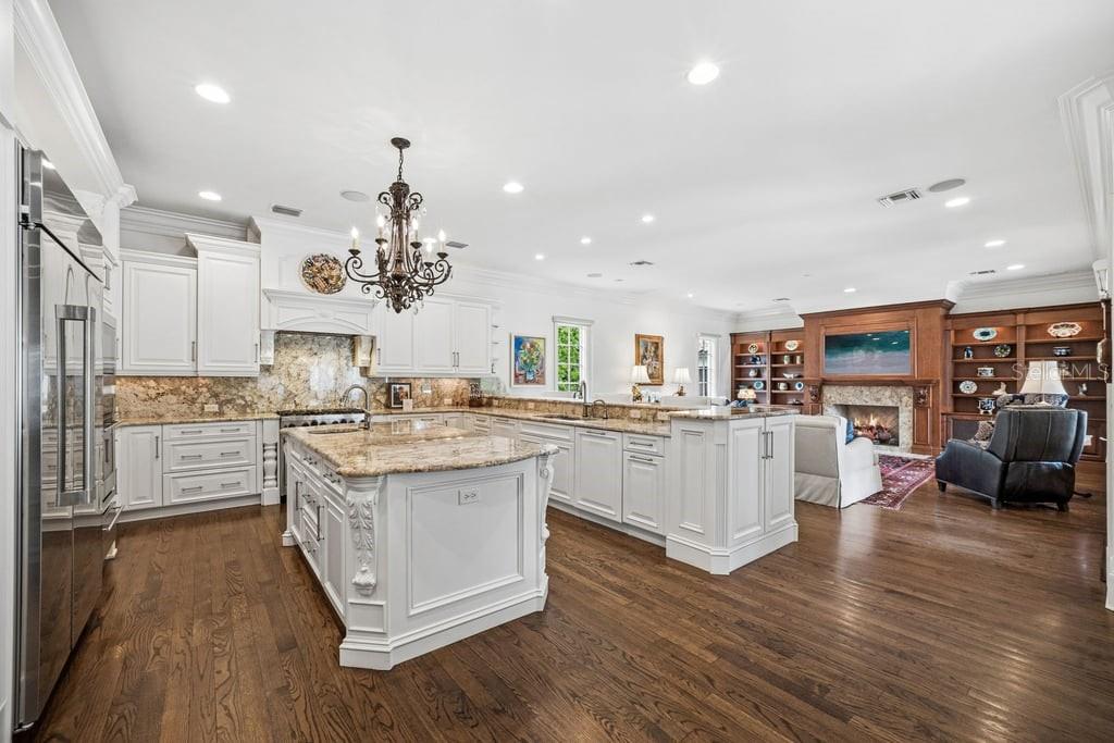 A spacious kitchen with white cabinetry, granite countertops, and a large island, open to a living room — 1571 WOODLAND AVENUE, WINTER PARK, FL
