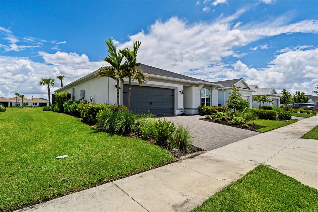 A single-story house with a gray garage, paved driveway, and palm trees under a cloudy sky — 16941 SAGE TERRACE, PUNTA GORDA, FL