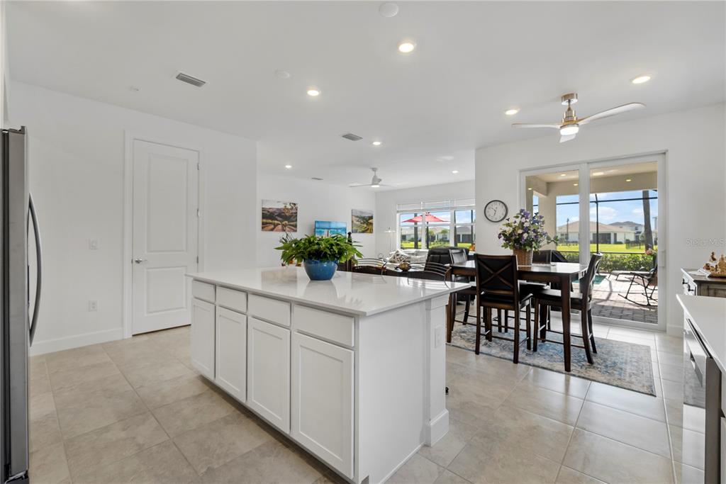 A kitchen island with a white countertop sits in an open-concept room with tile floors — 16941 SAGE TERRACE, PUNTA GORDA, FL