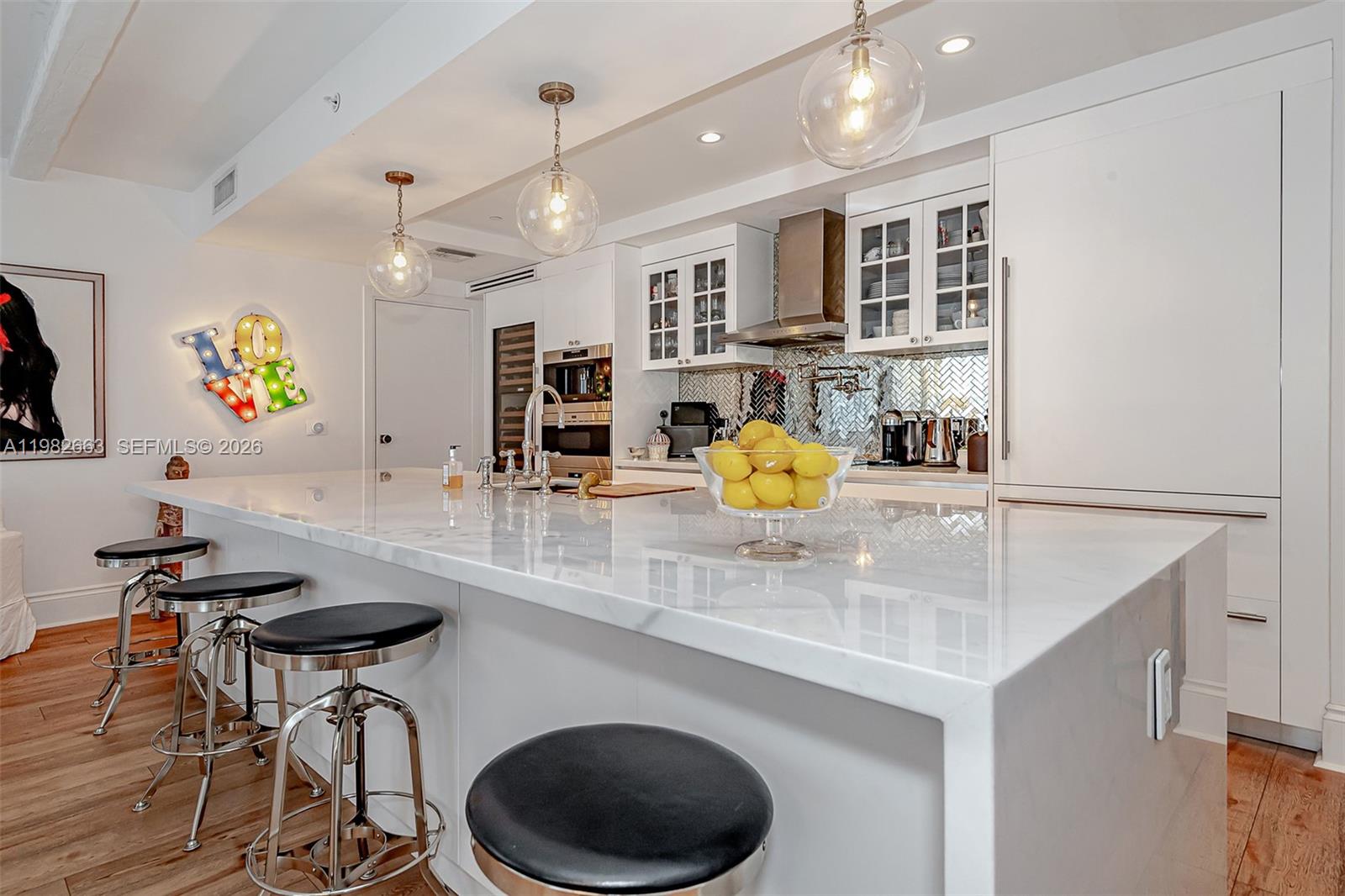 A modern white kitchen features a large marble island with bar stools and pendant lighting — 801 S Miami Ave # 4508, Miami FL 33130, MIAMI, FL