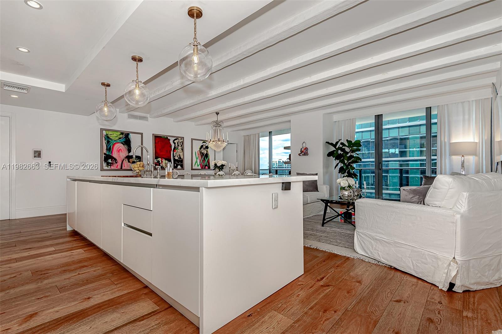A modern kitchen island with white cabinetry sits in an open-concept living area with wood floors — 801 S Miami Ave # 4508, Miami FL 33130, MIAMI, FL