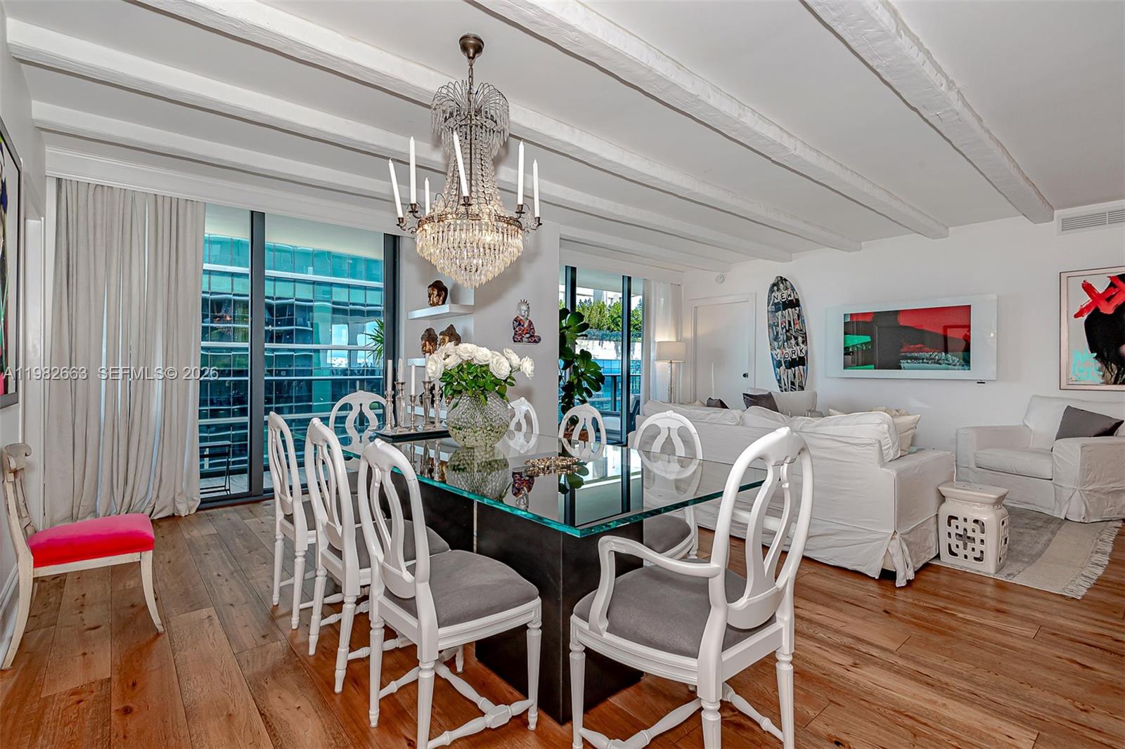 A dining room with a glass table, white chairs, a crystal chandelier, and wood flooring — 801 S Miami Ave # 4508, Miami FL 33130, MIAMI, FL
