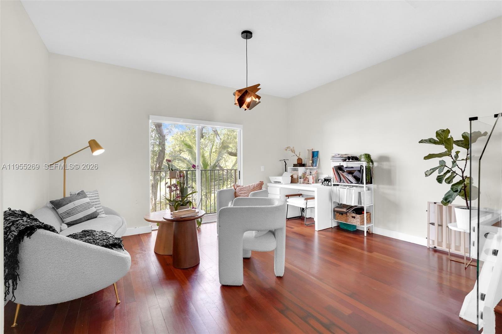 A living room with hardwood floors, a sofa, two armchairs, a desk, and a balcony — 738 NE 90th St # 207, Miami FL 33138, MIAMI, FL