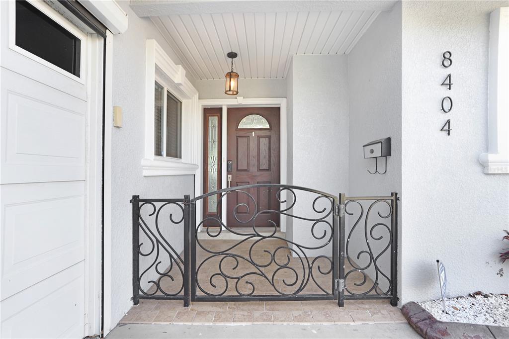 A front entryway features a brown door, a decorative metal gate, and house numbers — 8404 BLACKSTONE COURT, TAMPA, FL