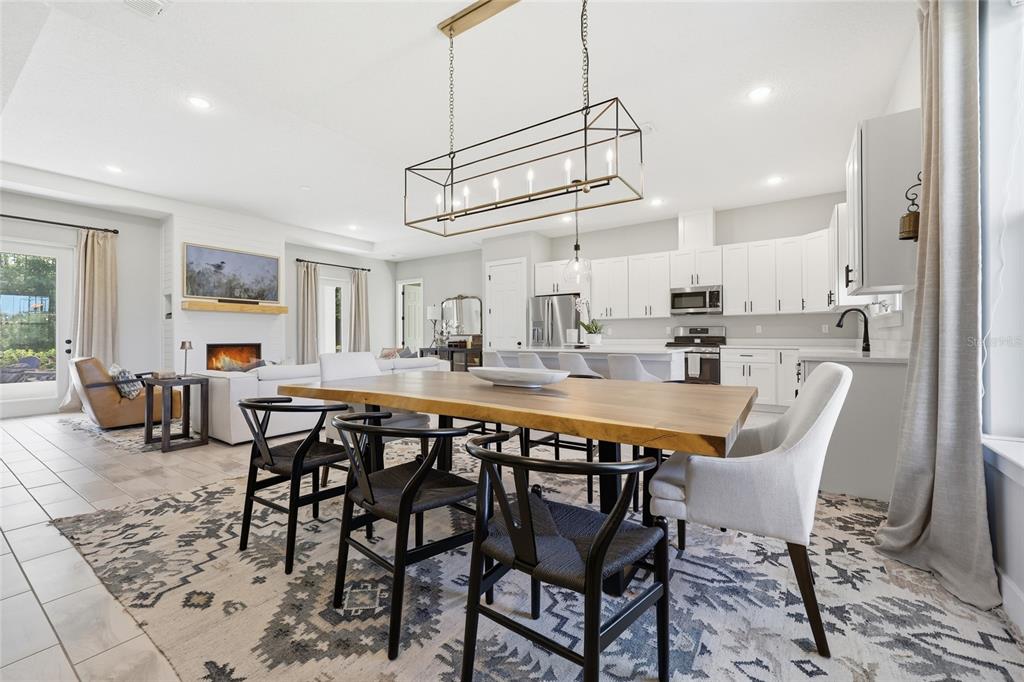 A dining area with a wooden table and black chairs sits before an open kitchen — 5777 SW 140TH AVENUE, OCALA, FL