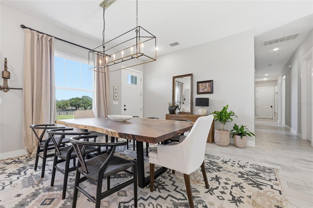 A dining room features a live-edge wood table, black chairs, and a rectangular pendant light — 5777 SW 140TH AVENUE, OCALA, FL